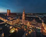 Nocny jarmark bożonarodzeniowy w Monachium. Rynek z oświetlonymi straganami i choinką, w tle Frauenkirche i Nowy Ratusz.