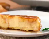 Un trozo de pan de calatrava bañado en caramelo, con una hoja de menta al lado.