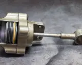 Metalowy element, prawdopodobnie część hamulca, z widocznymi sprężynami i żółtym pierścieniem. Wygląda, jakby miał zaraz **blow off** i wymagał naprawy.
