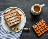 Gaufres de farine de châtaigne saupoudrées de sucre glace, servies avec du miel doré. Un délice gourmand.
