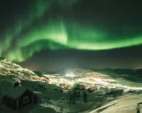 En snötäckt by i Sverige badar i det magiska skenet från norrskenet.