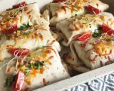 Tortilla z mięsem mielonym i serem, zapieczona z pomidorkami i kiełkami. Pyszne danie gotowe do podania.