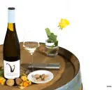 Flasche Gelber Muskateller Wein, Glas, Sternfrucht, Physalis, Litschi und Muskatnuss auf einem Holzfass.