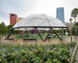 Modern playground under a geodesic dome in Parque Doña Casilda. Children play while parents relax on benches.