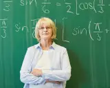 Nauczycielka matematyki przed tablicą z równaniami. Czy doczekamy się wcześniejszych emerytur dla nauczycieli?