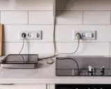 Deux plaques de cuisson à induction sont branchées sur des prises murales. L'une est une plaque portable, l'autre est intégrée.