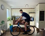 Mężczyzna w pozycji na rowerze gravel w kuchni, obok niego pies.