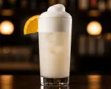 En krämig Ramos Gin Fizz med apelsinskiva, perfekt för en sofistikerad kväll.