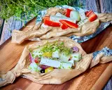 Zwei Päckchen mit Feta, Paprika, Zwiebeln und Kräutern warten darauf, gegrillt zu werden. Ein Genuss für den Gaumen!