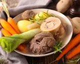 Un plat réconfortant de pot au feu, avec du bœuf, des carottes, des pommes de terre et des poireaux, garni de romarin.