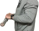 Person in grauem Hoodie macht einen Wrist Curl mit einer Hantel.