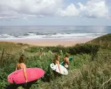 Drei Freunde mit Surfbrettern auf dem Weg zum Strand in Spanien. Die Wellen laden zum Surfen ein.