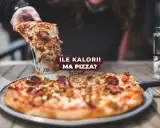Pyszny kawałek pizzy z ciągnącym się serem. Zastanawiasz się, ile kcal ma kawałek pizzy?
