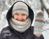 Uśmiechnięta kobieta w zimowym otoczeniu prezentuje ręcznie robione wzory czapek na szydełku i rękawiczki.