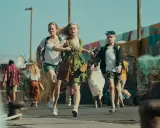 En grupp människor springer på en kaj, kanske i en scen från la palma serie. En ung flicka i grön klänning leder an.