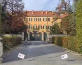 Ingresso di Villa San Martino ad Arcore, con cancello verde e alberi autunnali. Catena con cartelli di divieto di sosta blocca l'accesso.