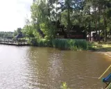 Malownicze łowisko Baroniok nad jeziorem, z drewnianym pomostem, domkami i zjeżdżalnią.