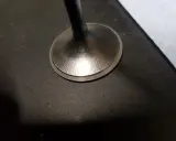 Metalowy zawór silnika po procesie docierania zaworów. Widoczna jest gładka powierzchnia styku.