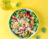 Pyszna sałatka z grillowanym halloumi, fasolką, jabłkiem i orzechami, udekorowana listkami bazylii.