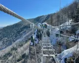 Zimowa przygoda na wiszącym moście nad przepaścią. Skalka pri Kremnici w śnieżnej odsłonie, z widokiem na zalesione zbocza.