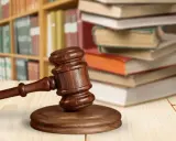 Martelletto da giudice su tavolo di legno, con libri e scaffali sullo sfondo. Simboleggia cosa succede dopo incidente probatorio.
