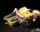 Kosz pełen chipsów i miseczka z dipem. Czy chipsy są zdrowe? To pytanie zadaje sobie wielu, patrząc na tę apetyczną przekąskę.