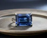 Anello con un magnifico zaffiro blu rettangolare, incastonato su un piatto metallico.