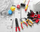Outils d'électricien sur un plan : fils, prises, tournevis, pinces, marteau, casque et gants pour installer le courant électrique.