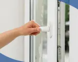 Mano girando la manija de unas ventanas de seguridad para casas, mostrando el mecanismo interno.