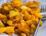 Un plato de patatas asadas doradas y crujientes, sazonadas con hierbas y especias, listas para ser disfrutadas con un tenedor.
