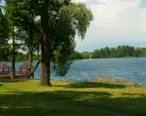 Malownicze jezioro Grabowo z altanami na pomoście, otoczone zielenią i drzewami.