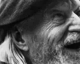 Primo piano di un uomo anziano con barba e cappello, il volto segnato dal tempo, come in un "giorno per giorno Ungaretti".