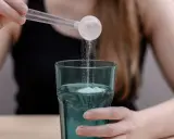Kiedy pić kolagen? Kobieta wsypuje proszek z miarki do szklanki z wodą, rozpoczynając swój codzienny rytuał.