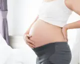 Brzuch kobiety w ciąży, widoczny od pasa w górę. To już 21 tydzień, czyli piąty miesiąc oczekiwania na dziecko.