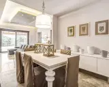 Un'elegante casa stile shabby chic moderno con tavolo da pranzo, divano e quadri botanici.
