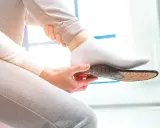 Une personne insère une semelle orthopédique dans sa chaussette. Une solution pour une pedicure remboursé.