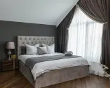Elegancka sypialnia z szarymi ścianami. Jaki kolor rolet pasuje do szarych ścian? Brązowe zasłony i jasne firanki tworzą przytulną atmosferę.
