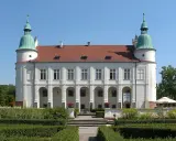 Baranów Sandomierski atrakcje: Zamek z arkadowym podcieniem i zielonymi wieżyczkami, otoczony zadbanym ogrodem.