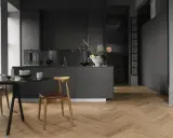 Cuisine moderne avec îlot central, chaises en bois et table en marbre. Le parquet en chevrons, bien que beau, est une mauvaise idée pour une cuisine.