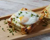 Croque monsieur con huevo frito y cebollino, un delicioso sándwich gratinado.