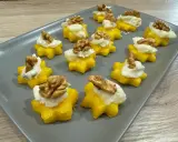 Stelline di polenta dorata con crema bianca e noci, perfetti antipasti di Natale per un tocco di sapore e colore.