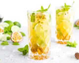 Zwei erfrischende Passion Fruit Mojitos mit Minze und Limette, umgeben von frischen Früchten und Eis.