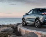 Nowy Peugeot 3008 hybryda na tle spokojnego morza i skalistego wybrzeża.