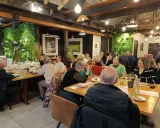 Un dîner convivial dans un restaurant à l'ambiance chaleureuse, où les convives savourent des mets qui incarnent la définition du "produit du terroir".