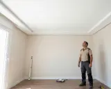 Un hombre admira el nuevo pladur techo con molduras decorativas.