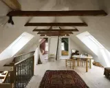 Idee per ristrutturare casa antica: mansarda luminosa con travi a vista, tappeto persiano, teepee e tavolino per bambini.