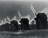 Mulini a vento in un campo, con un effetto di solarizzazione man ray che illumina le pale.