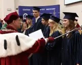 Uroczystość wręczenia dyplomów na studiach w Trójmieście. Absolwenci w togach odbierają gratulacje.