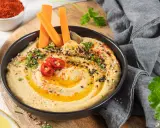 Hummus cremoso con bastones de zanahoria, pimientos rojos y semillas. Un snack saludable ideal para el embarazo.