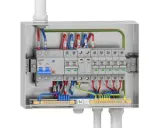 Metalowa obudowa z wyłącznikami i przewodami. Widoczna instalacja elektryczna natynkowa z zabezpieczeniami i listwami zaciskowymi.